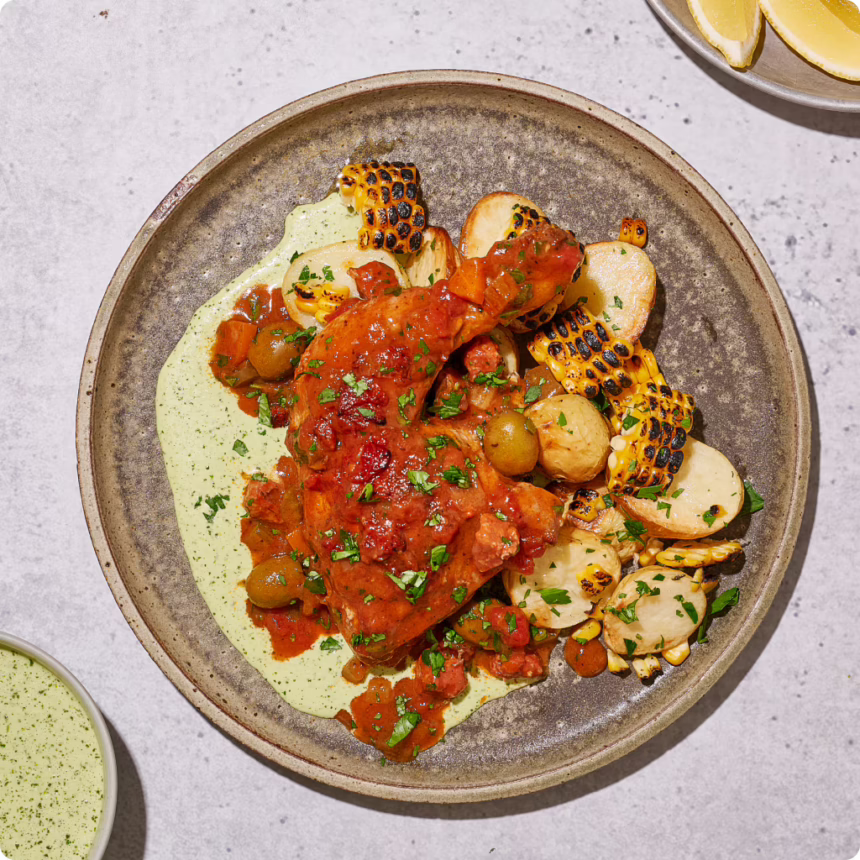 Slow-braised chicken in tomato sugo with aji verde, roasted potatoes, olives and charred corn.