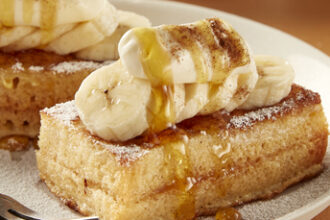 Banoffee French toast topped with sliced banana, cream, caramel sauce and cinnamon sugar.