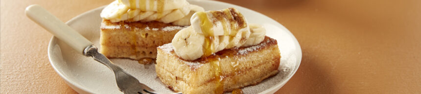Banoffee French toast topped with sliced banana, cream, caramel sauce and cinnamon sugar.