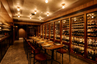 Circl’s warmly lit dining room with wooden tables and a glass-fronted cellar filled with wine bottles.