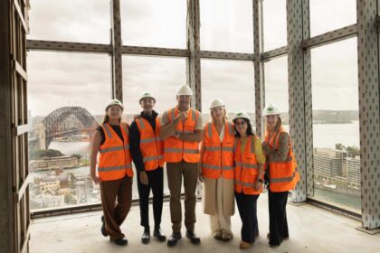 Curtis Stone and the Waldorf Astoria Sydney project team wearing high-visibility vests and hard hats at the hotel’s construction site overlooking Sydney Harbour.