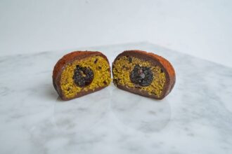 Dubai chocolate cookie cut in half to reveal pistachio kataifi filling and a molten chocolate centre.