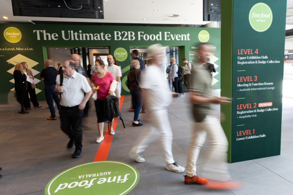 Visitors entering Fine Food Australia beneath signage describing it as the ultimate B2B food event.