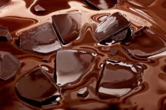 Broken dark chocolate pieces partially submerged in glossy melted chocolate.