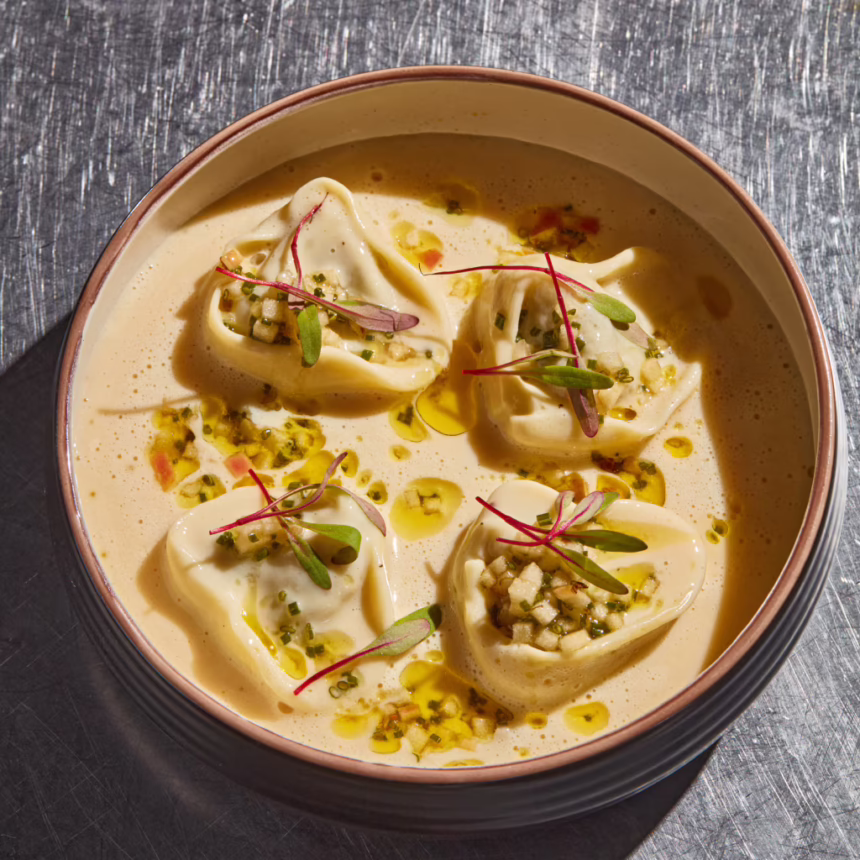 Forest mushroom tortellini served in a creamy sauce with herb oil, diced garnish and microgreens.