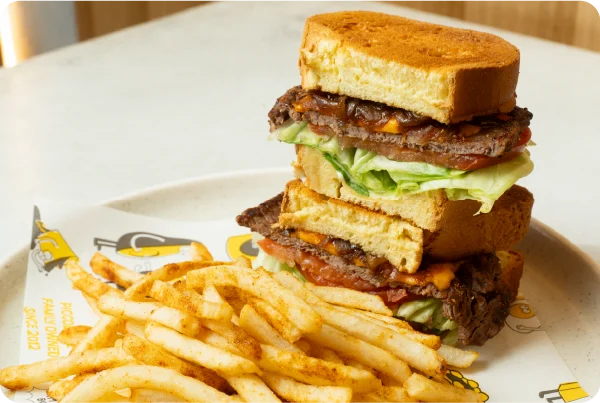 Piccolo Me steak sandwich made with sous vide beef, lettuce, tomato and sauce, served with seasoned fries.