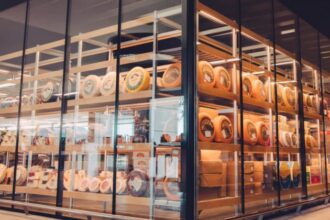 Wheels and blocks of specialty cheese displayed on shelves behind glass.