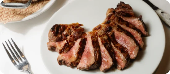 Sliced medium-rare steak served on a white plate.