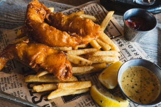 Battered fish and chips served with lemon wedges and two dipping sauces.