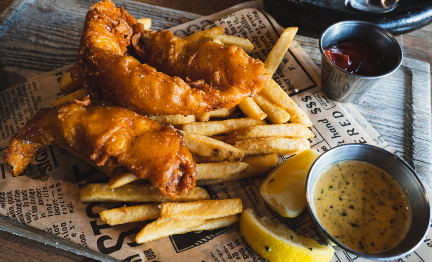 Battered fish and chips served with lemon wedges and two dipping sauces.