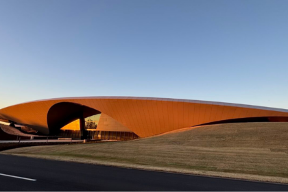 Modern poultry processing facility with a sweeping orange roof and landscaped grounds