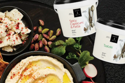 Birch & Waite 2.2kg tubs of Spicy Capsicum & Fetta and Tzatziki dips surrounded by flatbread, feta, pistachios and herbs.