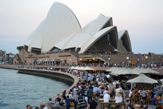Crowds dining at Opera Bar on the Sydney waterfront with the Sydney Opera House in the background.