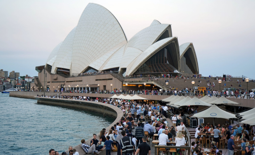 Crowds dining at Opera Bar on the Sydney waterfront with the Sydney Opera House in the background.