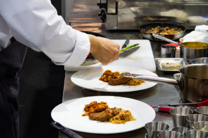 A chef plating individual meals in a commercial kitchen.
