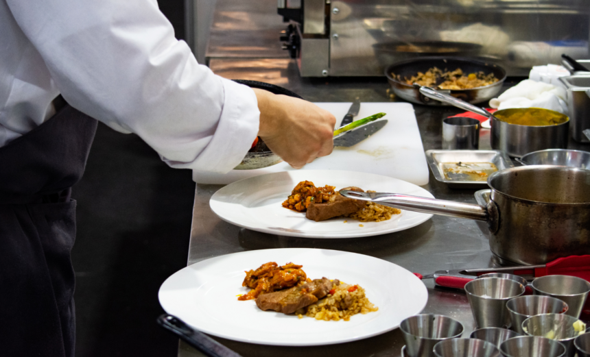 A chef plating individual meals in a commercial kitchen.