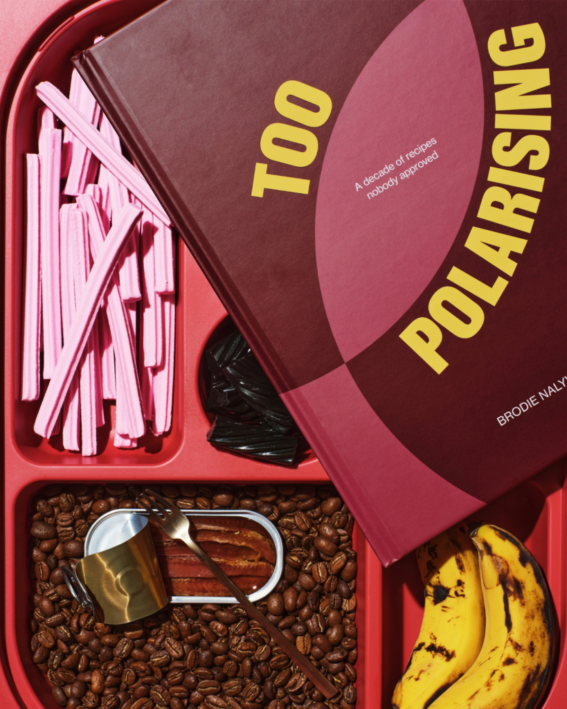 Too Polarising cookbook by Brodie Nalywajko styled with pink sweets, coffee beans, bananas and tableware in a colourful flat lay.