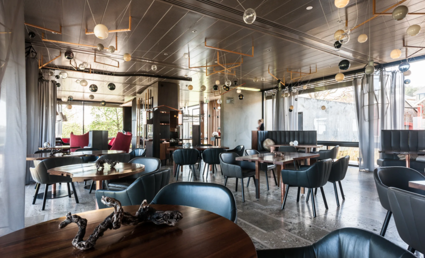 Interior of Magill Estate Restaurant in Adelaide, South Australia, featuring timber dining tables, dark leather seating and suspended glass pendant lights.
